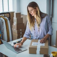 Women, owener of small business packing product in boxes, preparing it for delivery.