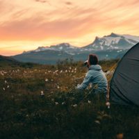 Tent on a mountain top during sunset, man looking on view. Rago National Park, Norway